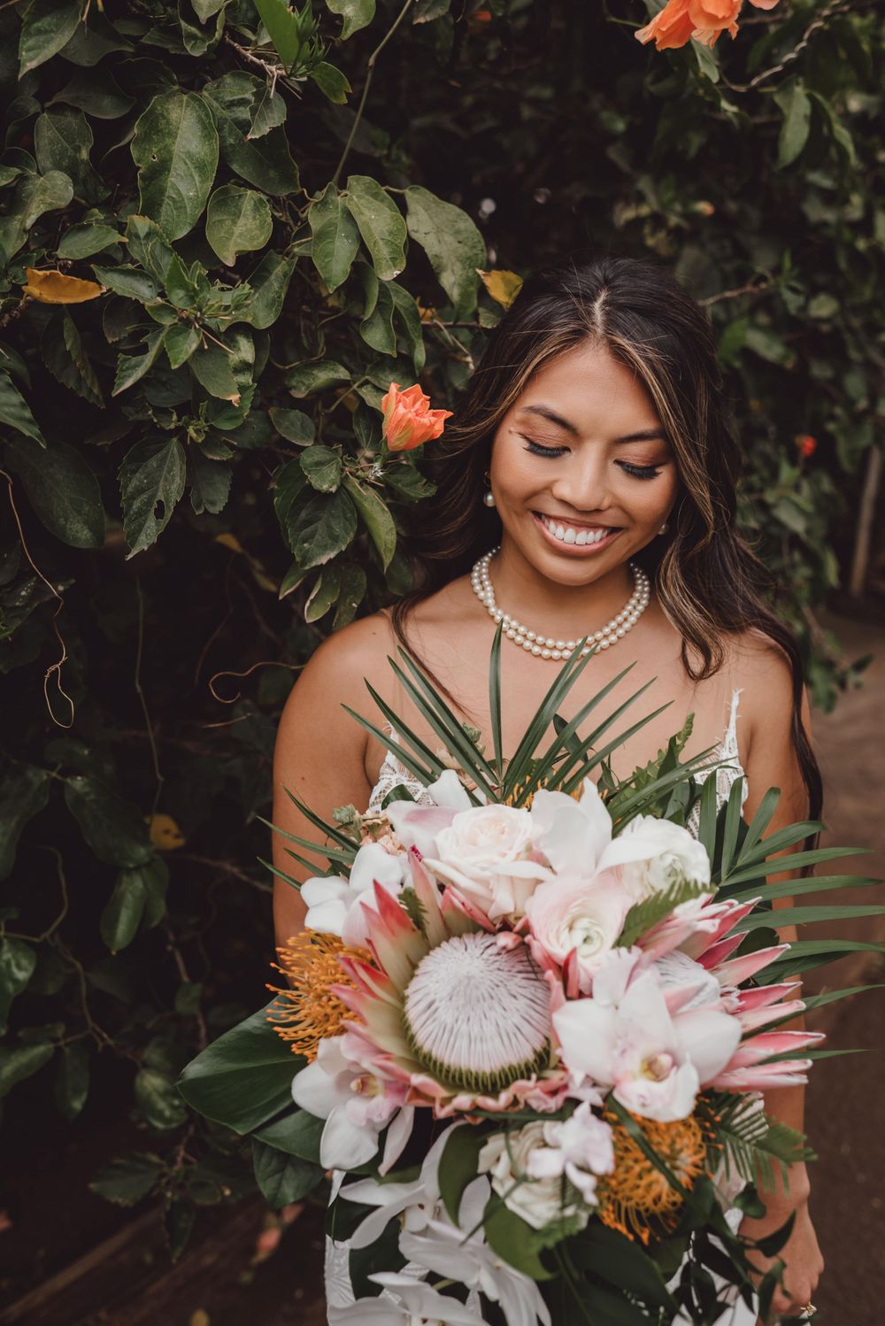 Stunning tropical wedding bouquet featuring white orchids, protea flowers and palm fronds.
