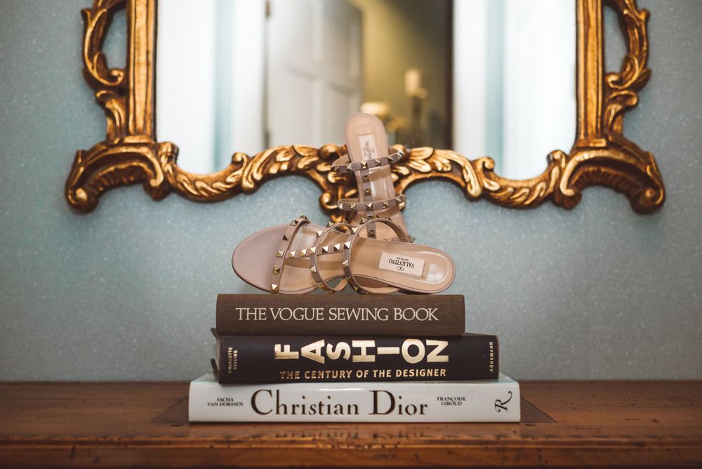 Vintage books including Vogue, Wizard of Oz, and Christian Dior displayed on shelf.
