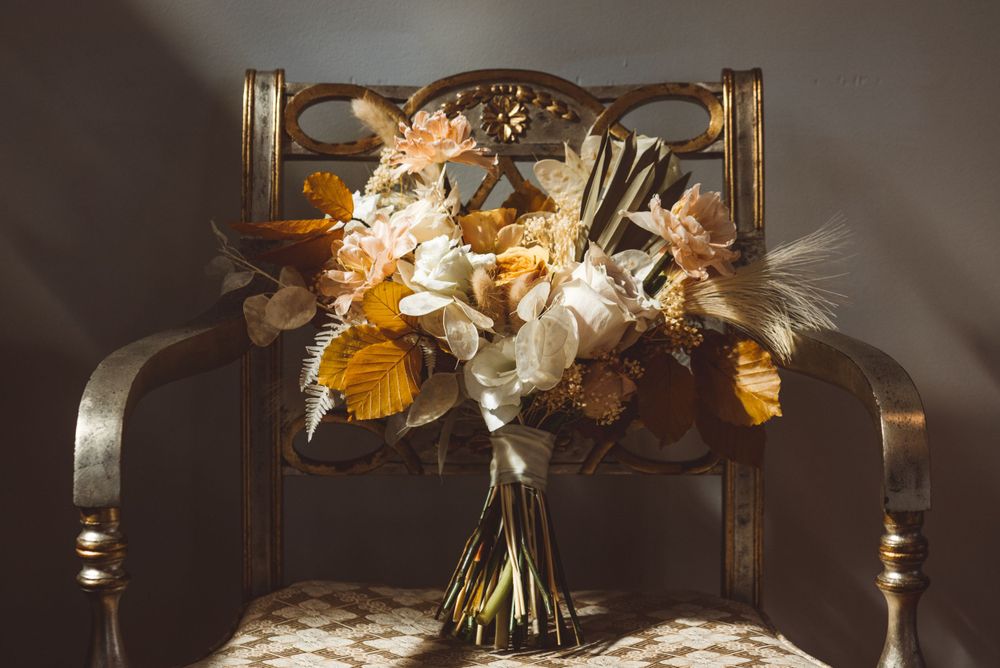 Elegant floral arrangements with white and orange flowers displayed in ornate gold frames.