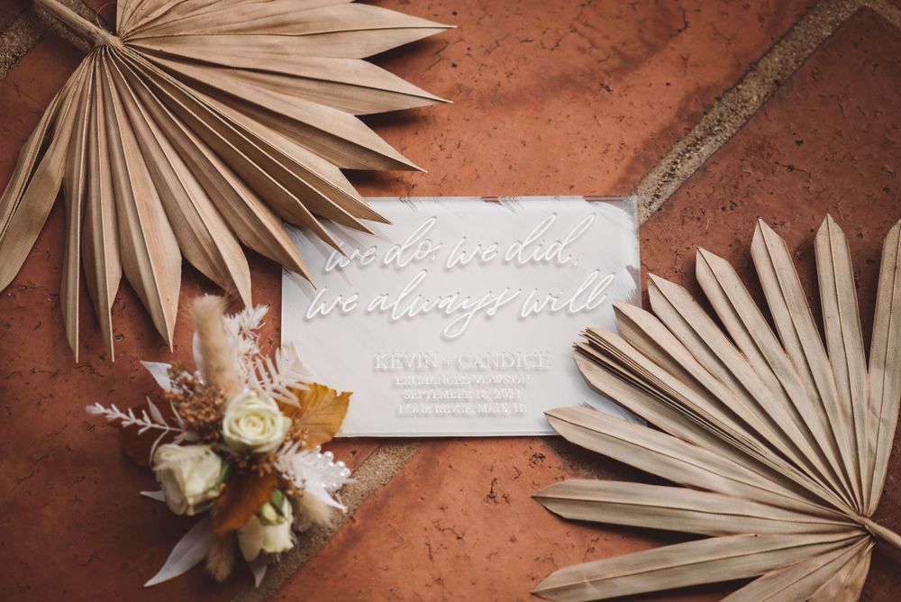 Wedding stationery and dried palm leaves arranged on terracotta surface.