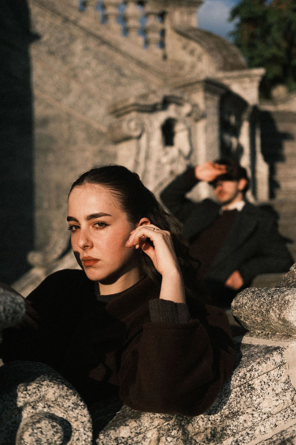 A sequence of moody portrait photographs taken at sunset against stone architecture in dramatic lighting.