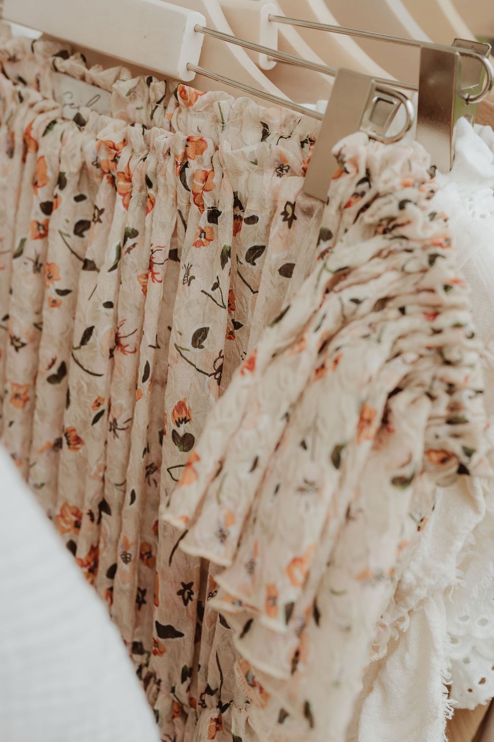 Een rij witte jurken met verfijnde bloemendetails, zorgvuldig opgehangen in de client closet.