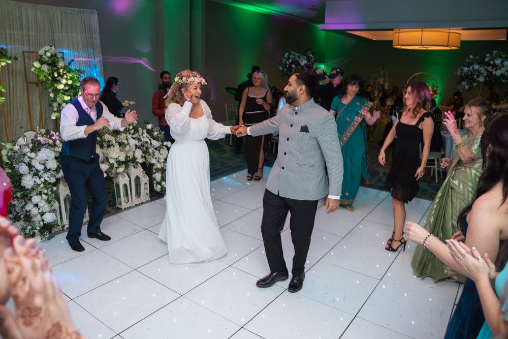 Wedding reception dance floor with colorful lighting and guests celebrating.