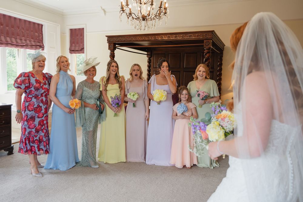 Elegant wedding party gathering in a grand room with crystal chandelier and classic decor.