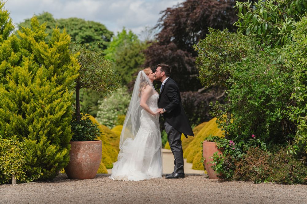Wedding couple sharing romantic moments in a lush garden setting with beautiful landscaping.