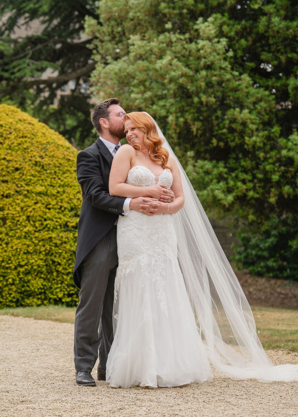 Romantic outdoor wedding portraits on a gravel path with yellow flowers in the background.