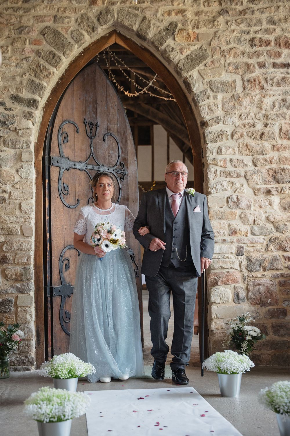 Stone archway entrance to church decorated with white flowers for wedding ceremony.