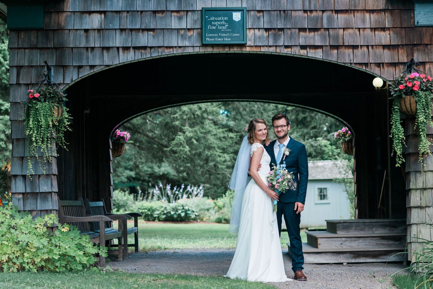 A rustic wooden building serves as a backdrop for a wedding photo session.
