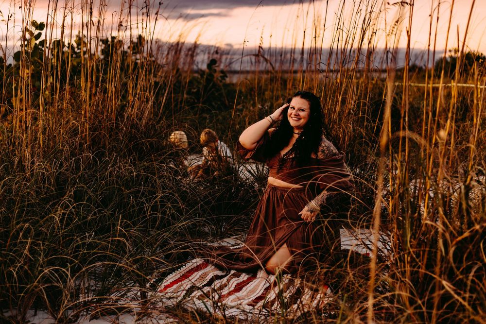 A golden sunset illuminates tall reeds and grass in a field during a romantic outdoor photoshoot.