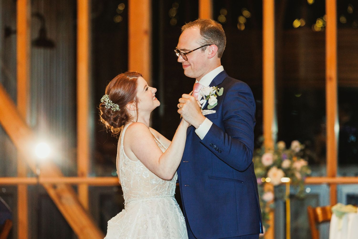 Intimate dance moment captured during wedding reception in rustic venue with warm lighting.