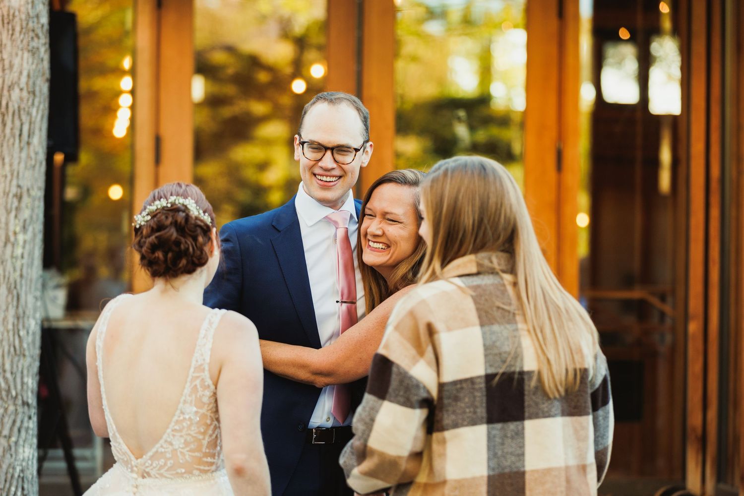 Wedding reception guests mingle and celebrate in a warmly lit rustic indoor venue.