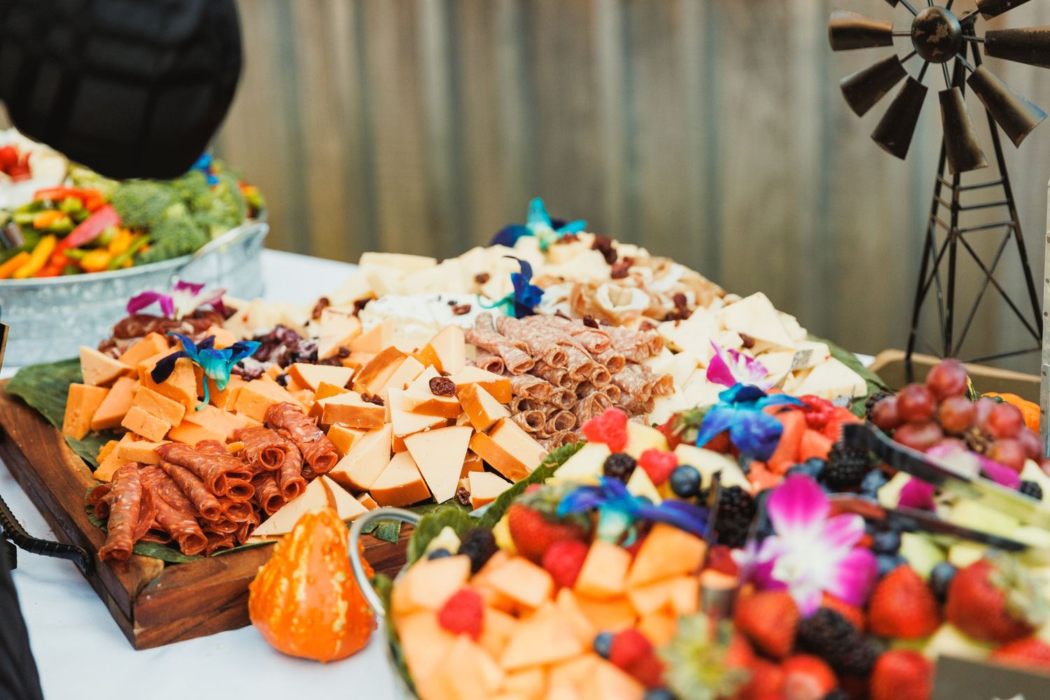 Elegant wedding reception buffet table with colorful appetizers, fruits and decorative displays.