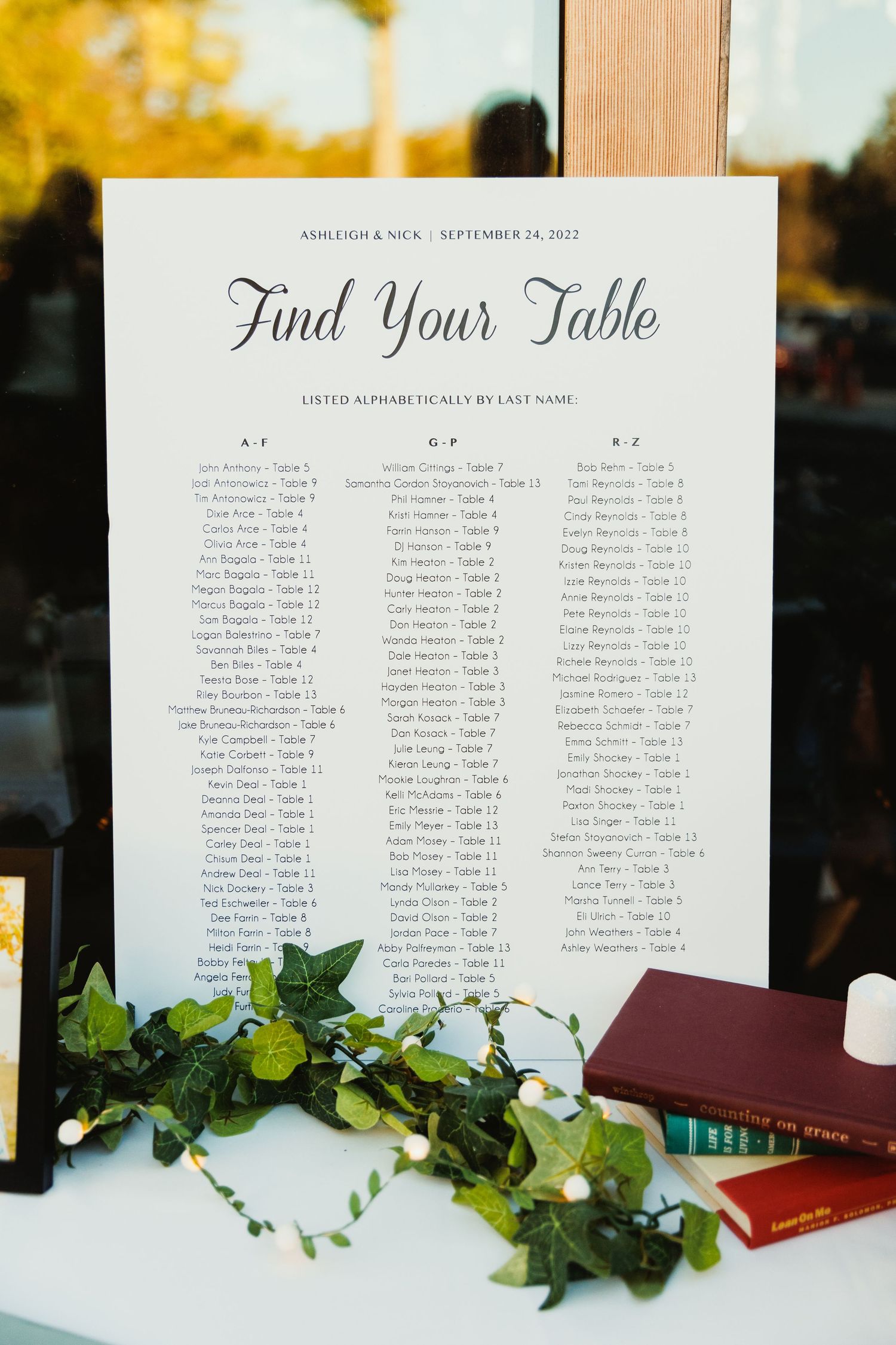 Wedding seating chart display with greenery accents and elegant calligraphy.