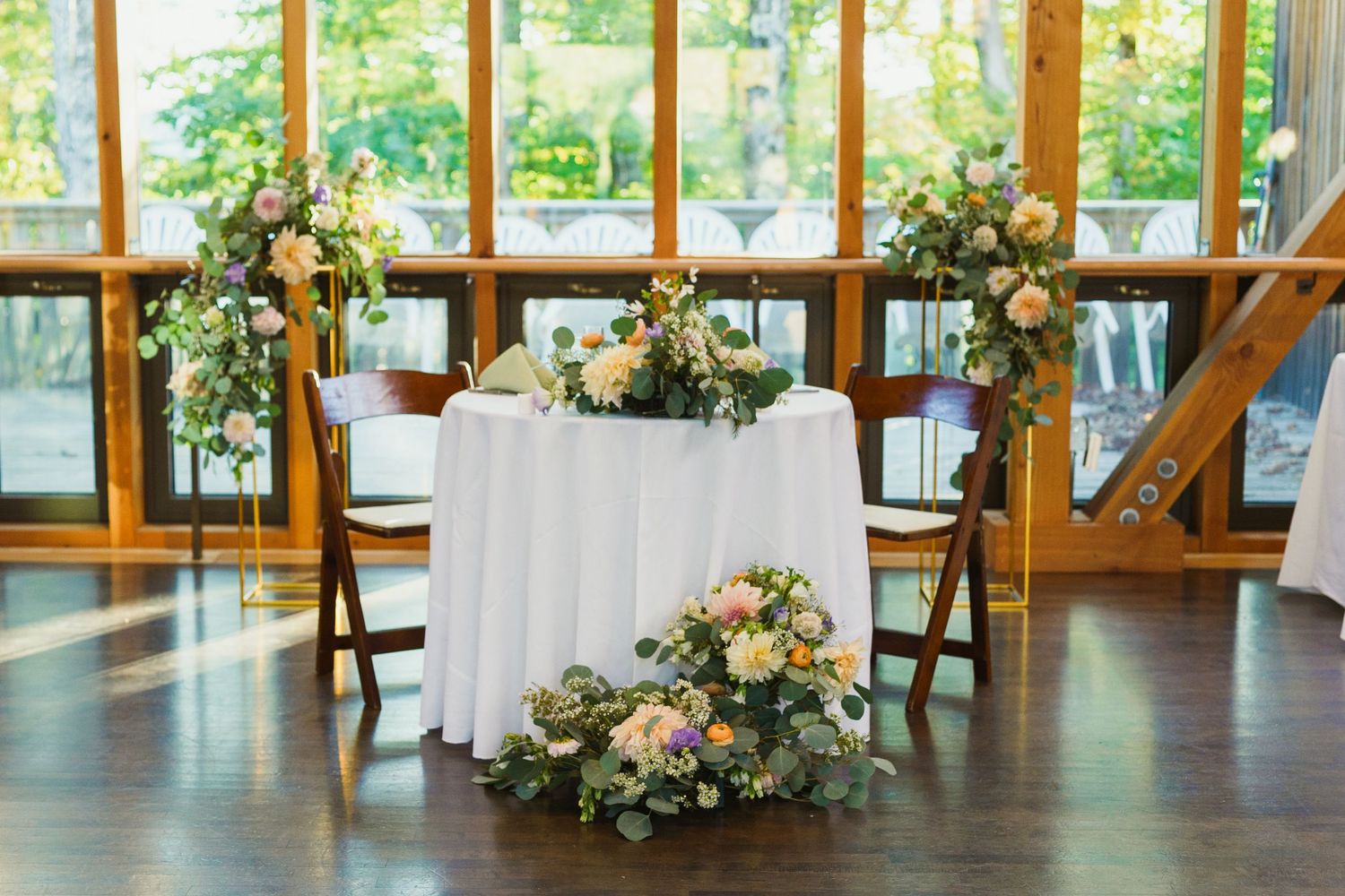 Rustic wedding venue interior with wooden beams and large windows overlooking natural scenery.