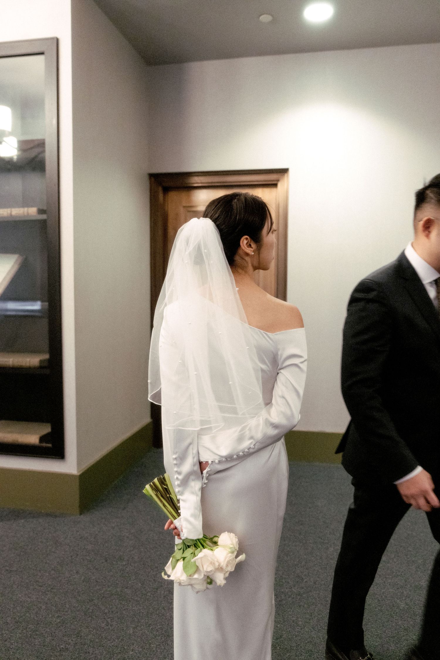 Wedding couple walking through hallway with bride holding bouquet.
