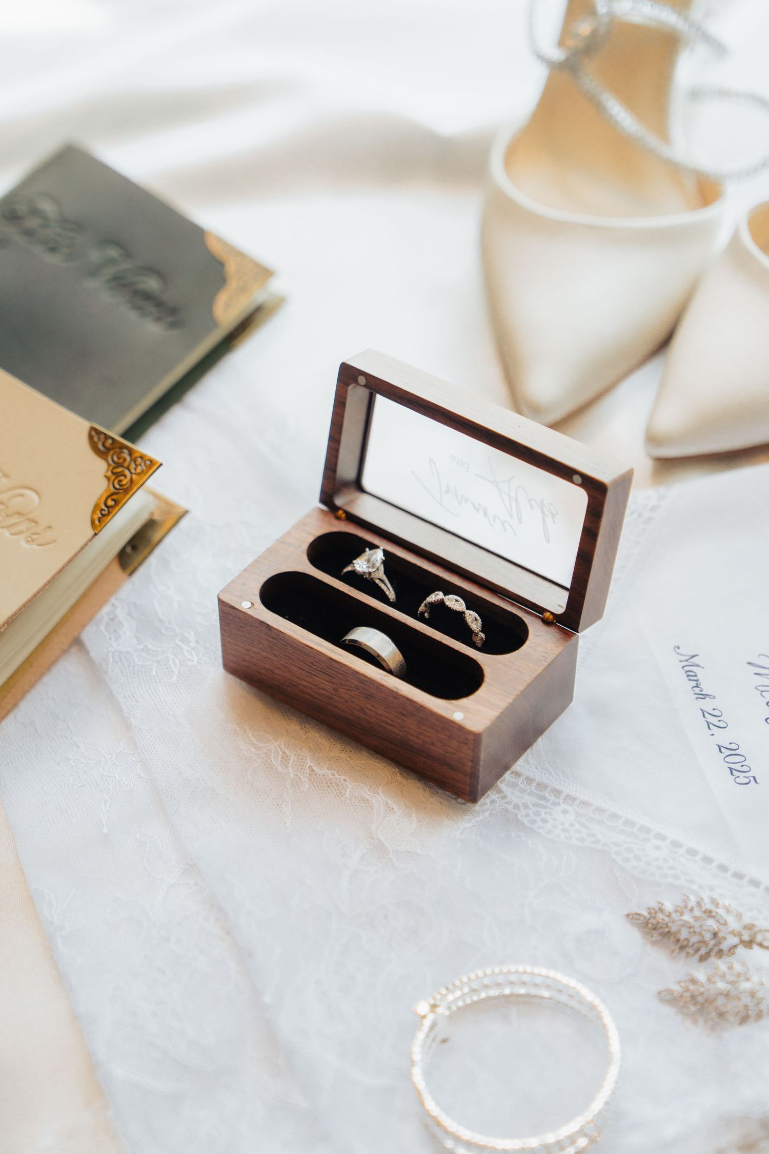 Wedding rings displayed in an elegant wooden box on white fabric.