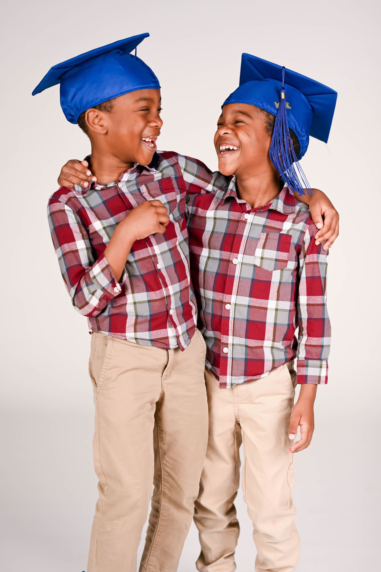 Young graduates in blue caps and plaid shirts share joyful moments together.
