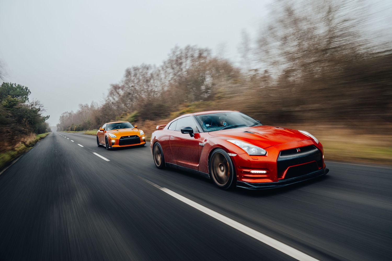 Orange Nissan GT-R sports car speeds down an empty highway during motion photography session.