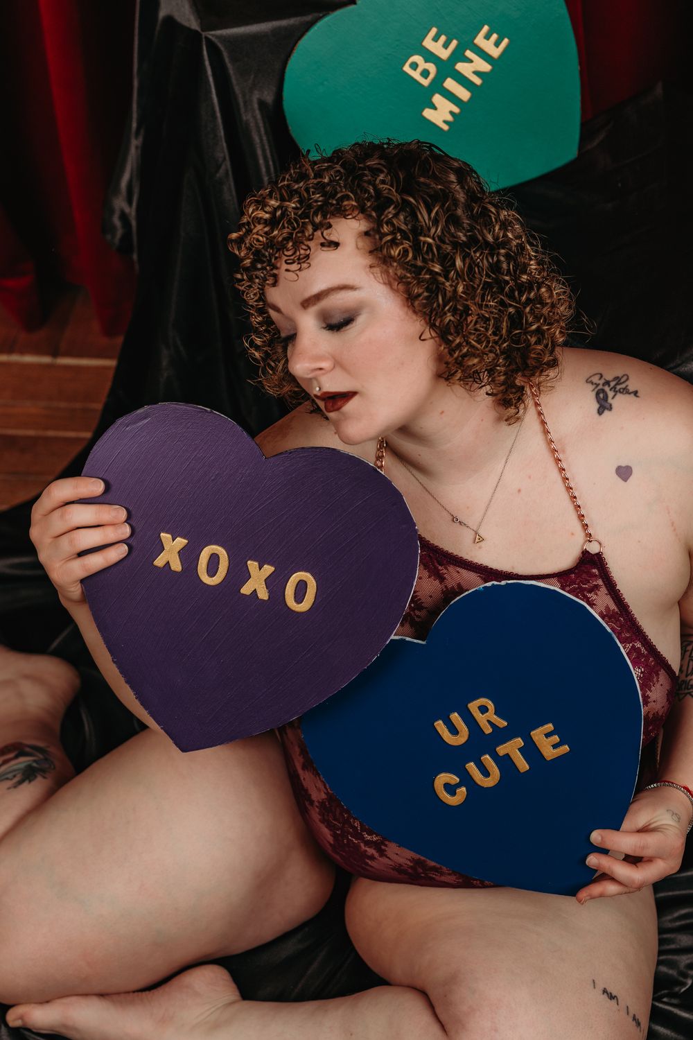Heart-shaped signs with gold lettering spell out a message against a dark red background.