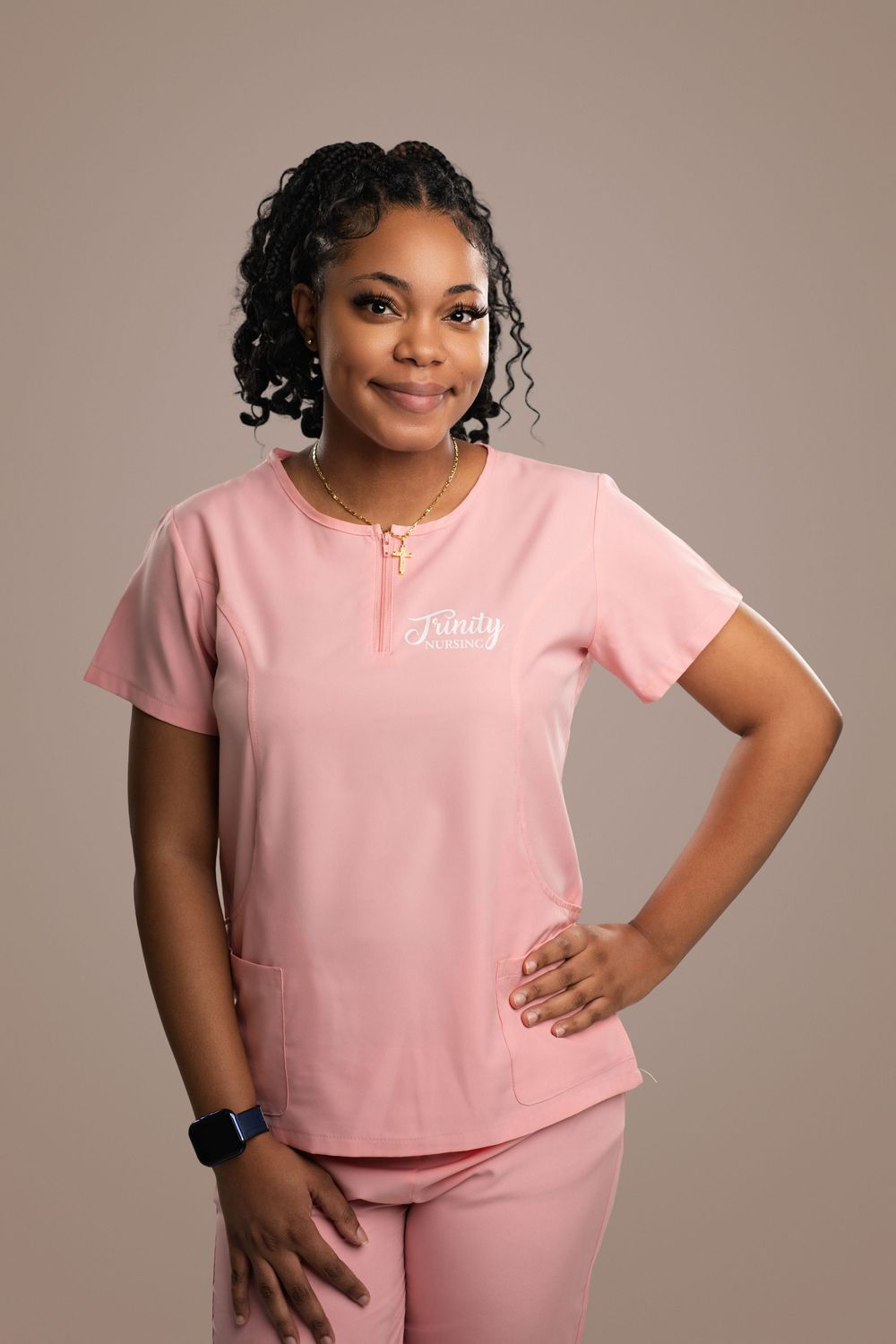 Healthcare worker in pink uniform strikes confident pose during studio photoshoot.