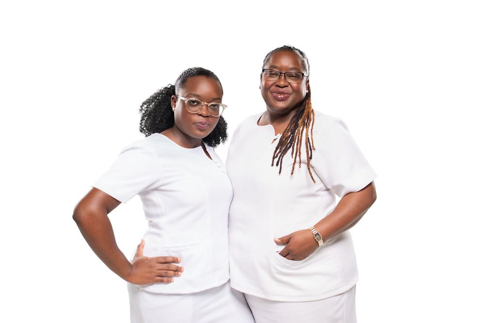 Two people wearing white t-shirts pose together while smiling in a studio setting.