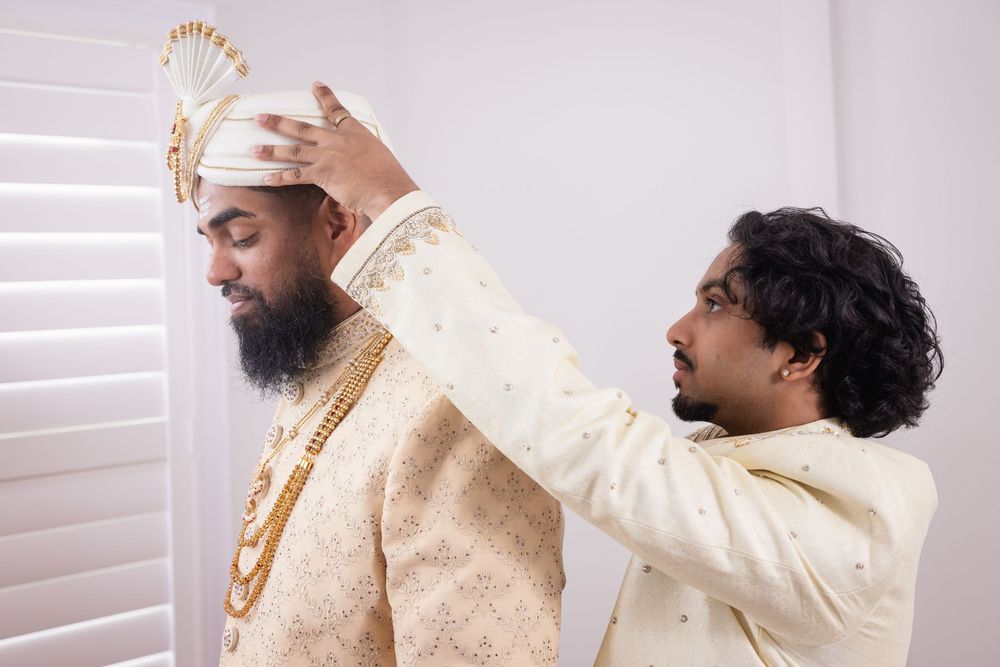 Two people in traditional Indian wedding attire embrace and laugh together during a joyful celebration moment.