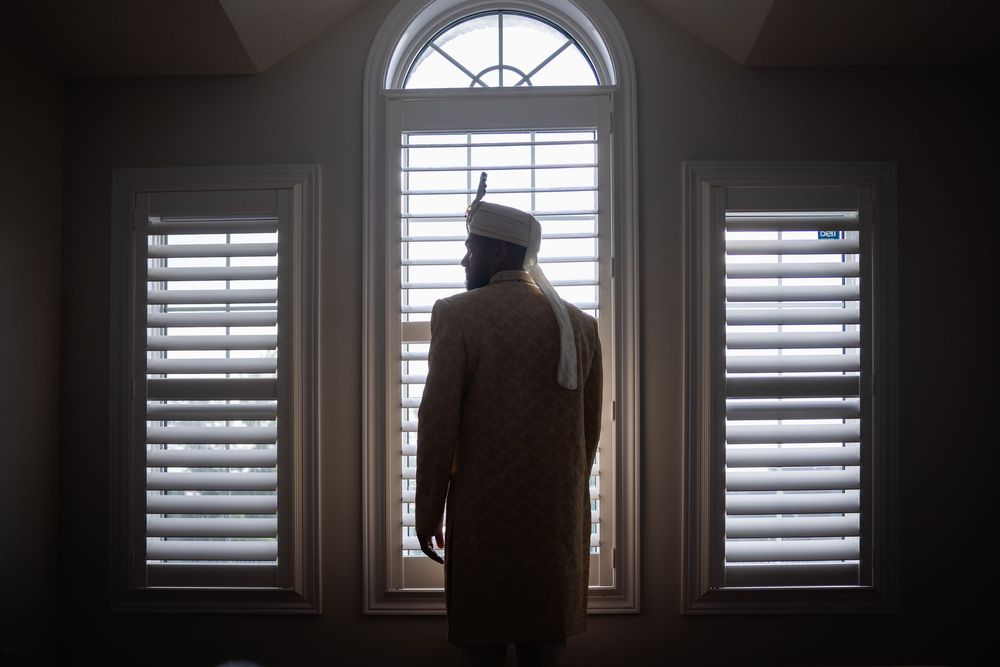 A series of window shutters in a dark room casting dramatic shadows and light patterns through the slats.
