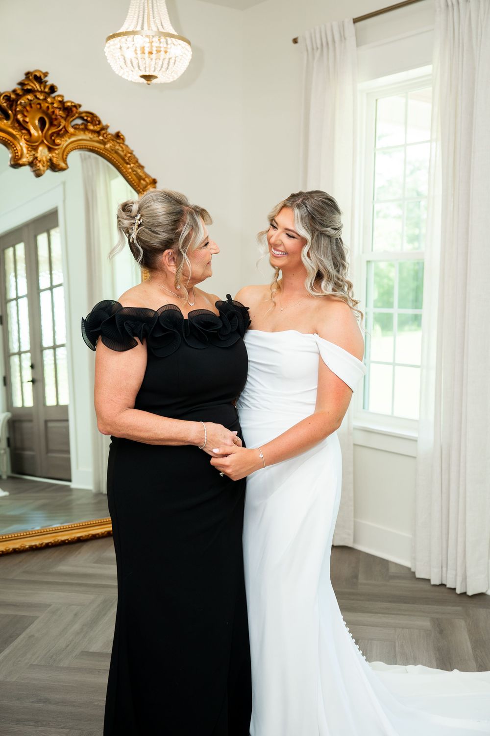 Intimate moment captured in an elegant room with herringbone floors and ornate gold mirror.