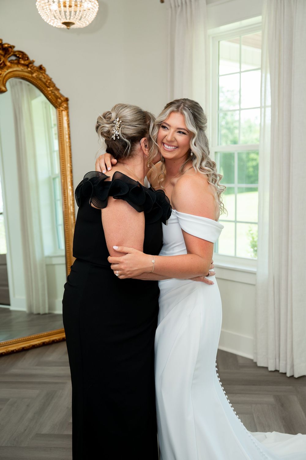 Joyful embrace captured in an elegant room with crystal chandelier and gold mirror.