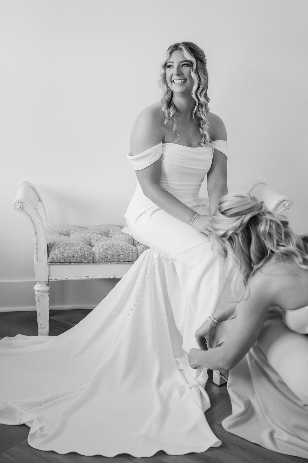 A bride in a classic white wedding gown poses gracefully on an antique chaise lounge.