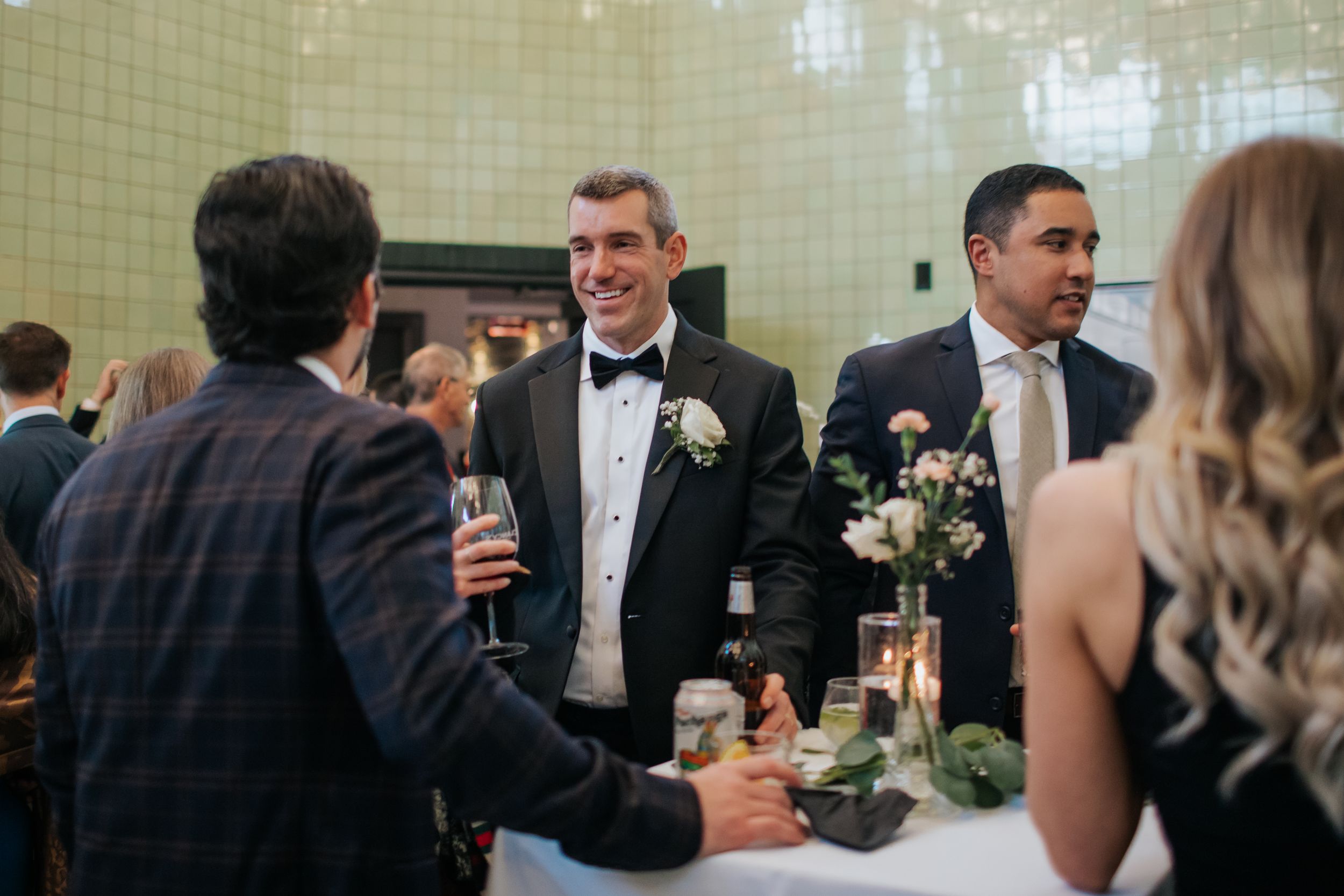 Wedding guests gather around a table for drinks and conversation at an elegant reception.