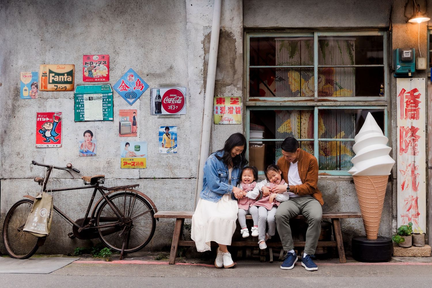 A row of vintage bicycles parked against a weathered wall with colorful posters and advertisements in an Asian street scene.