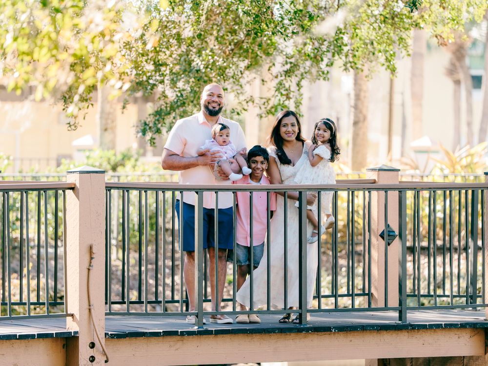 Wedding guests gather on a terrace railing overlooking a scenic outdoor venue during a celebration.
