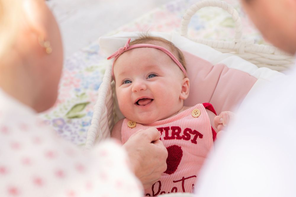 A series of seven heartwarming photos showing a baby in pink outfits lying on soft blankets and smiling.