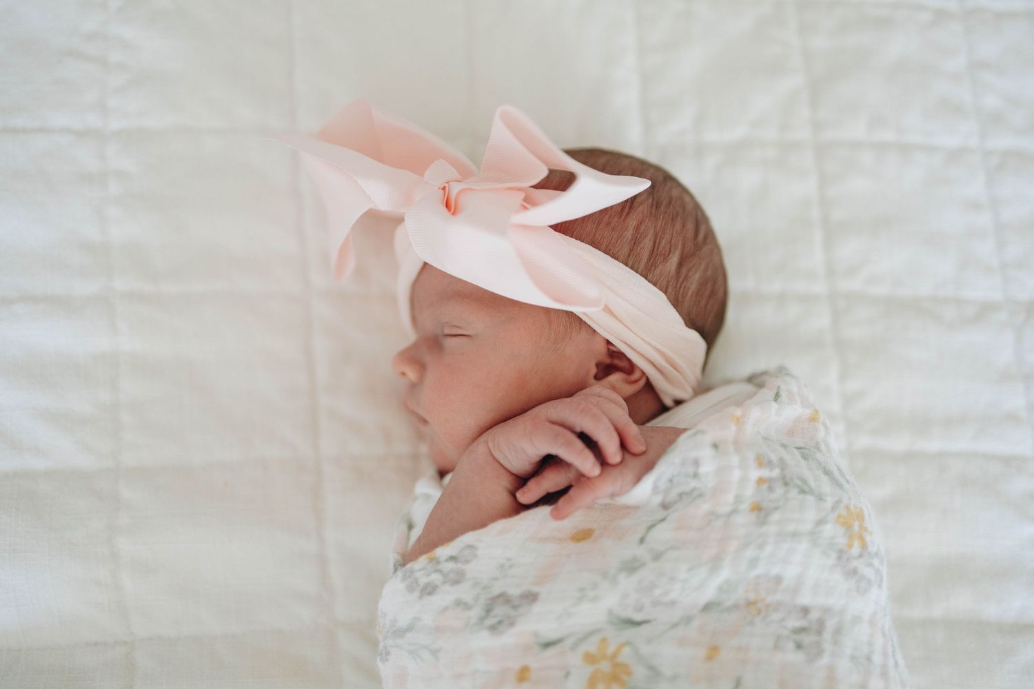 Newborn baby resting on a blanket wearing a soft headband.