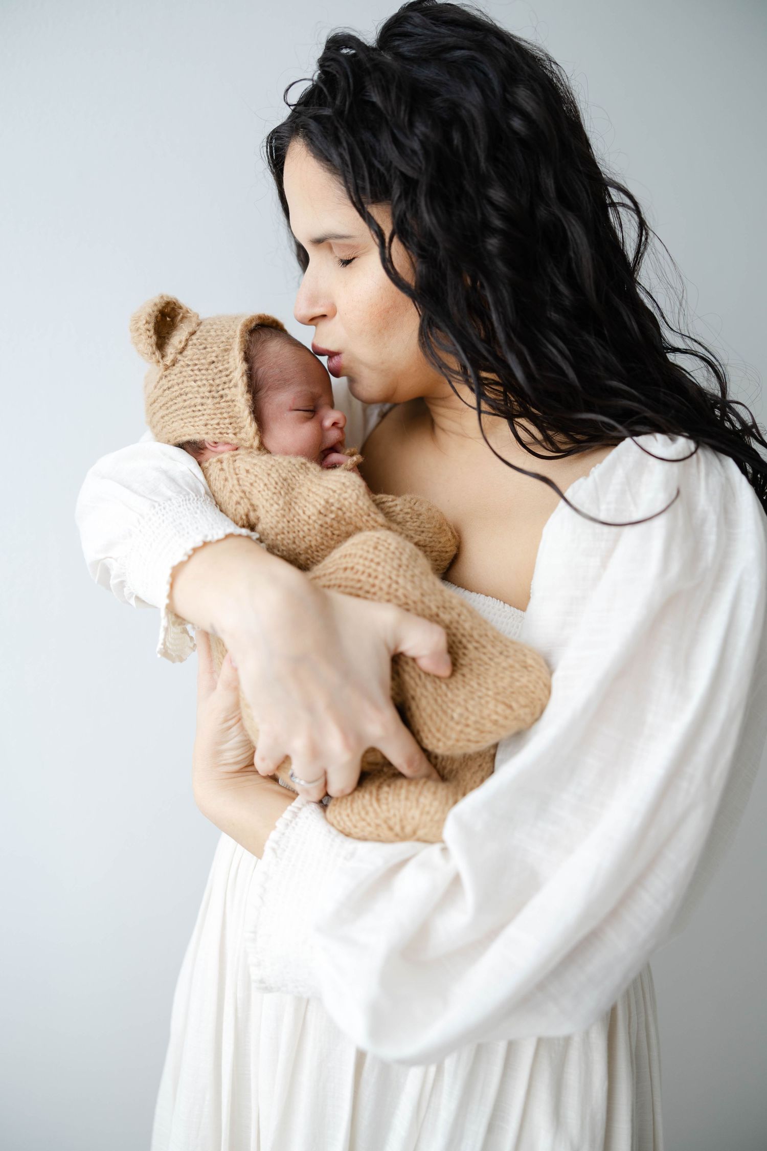 Mother holding her newborn baby near a window in soft natural light during a lifestyle newborn session.