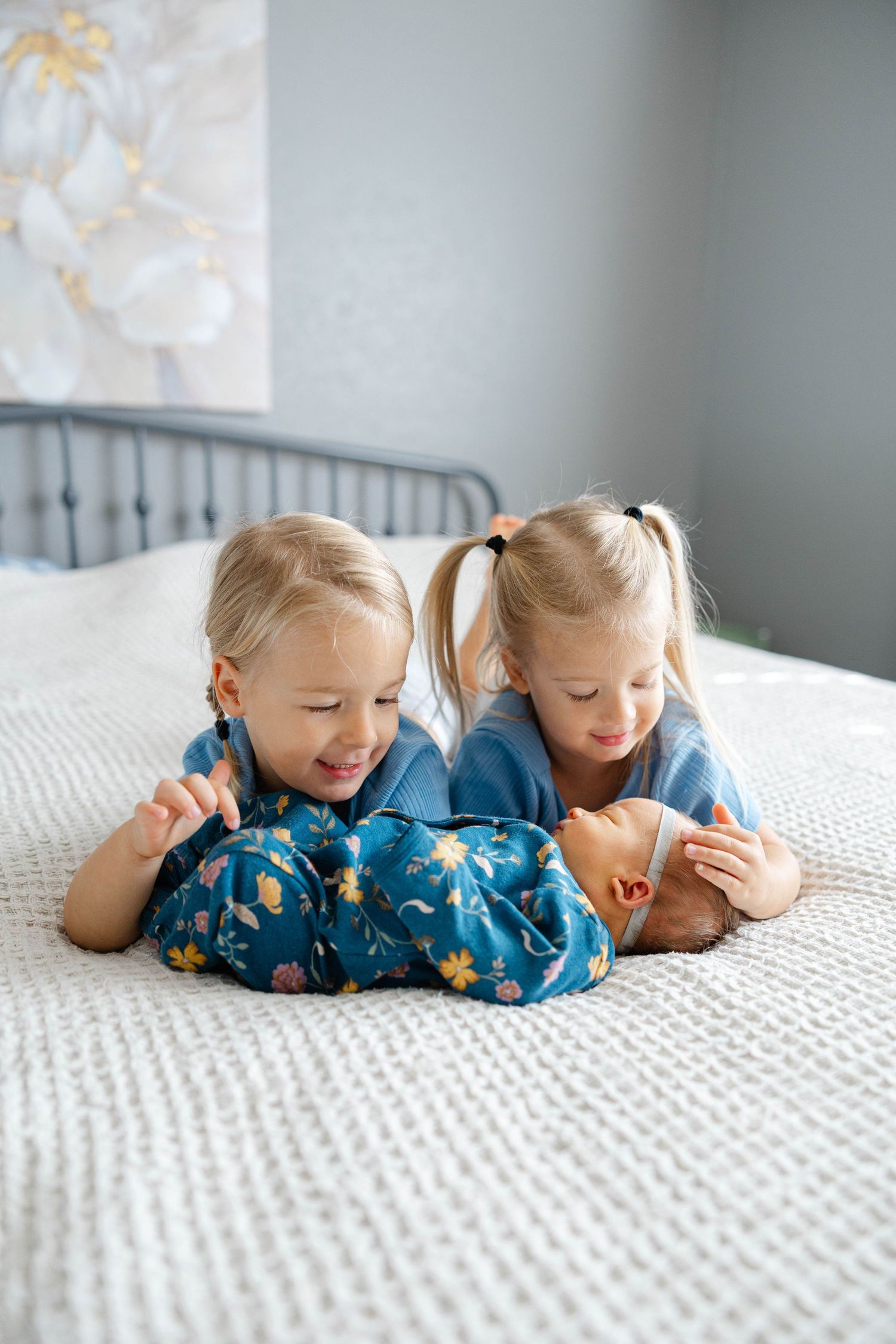 Sibling lifestyle portrait featuring two young children lying together on a bed during a family photography session.
