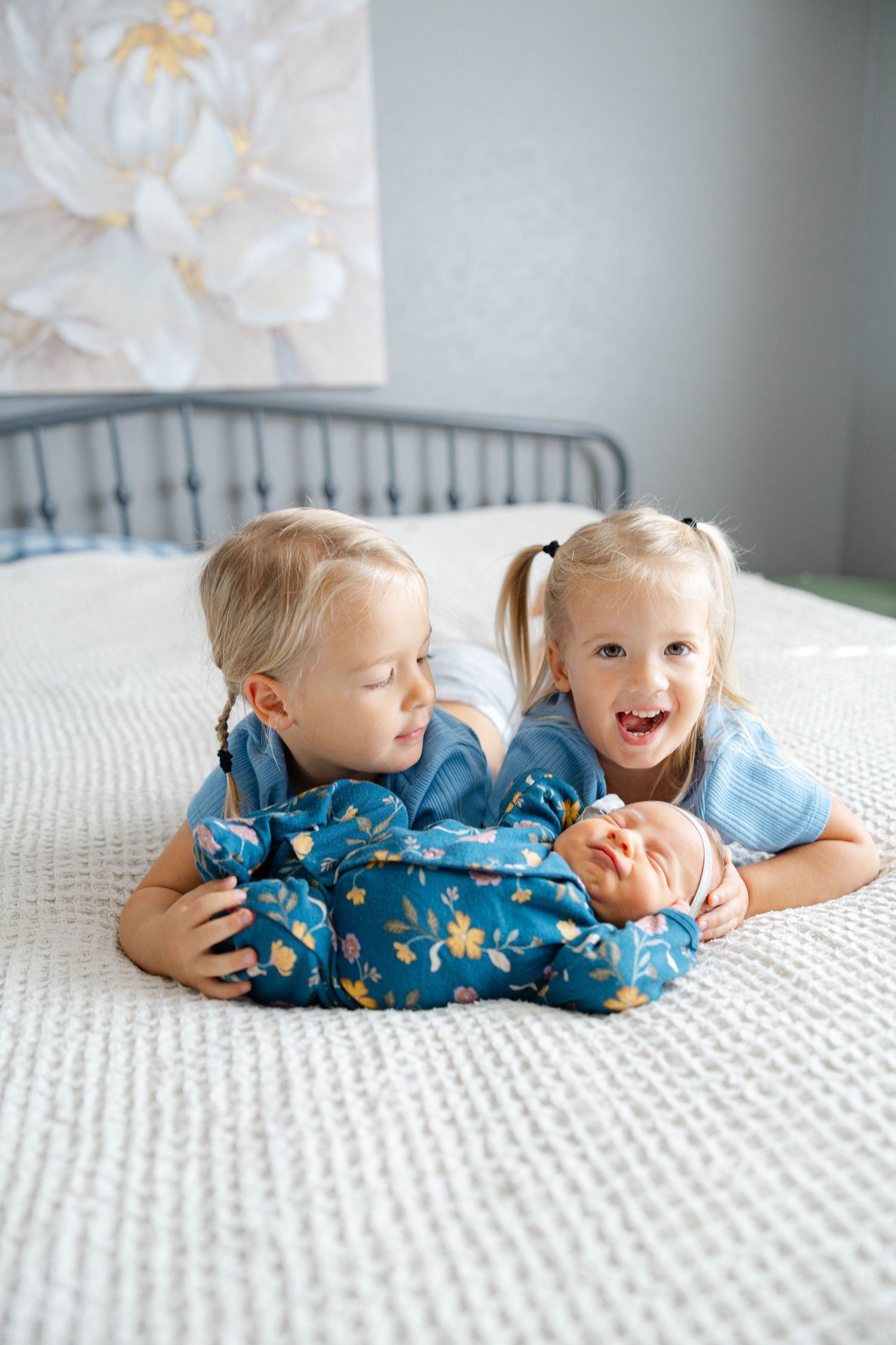 Sibling lifestyle portrait featuring two young children lying together on a bed during a family photography session.