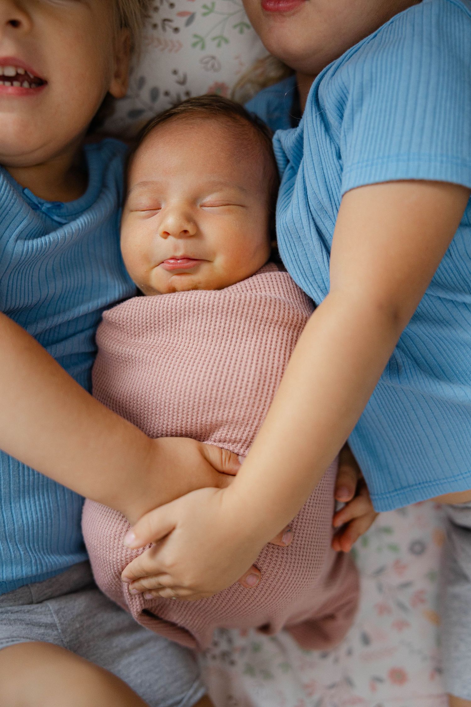 Newborn baby held by siblings during a family photography session.
