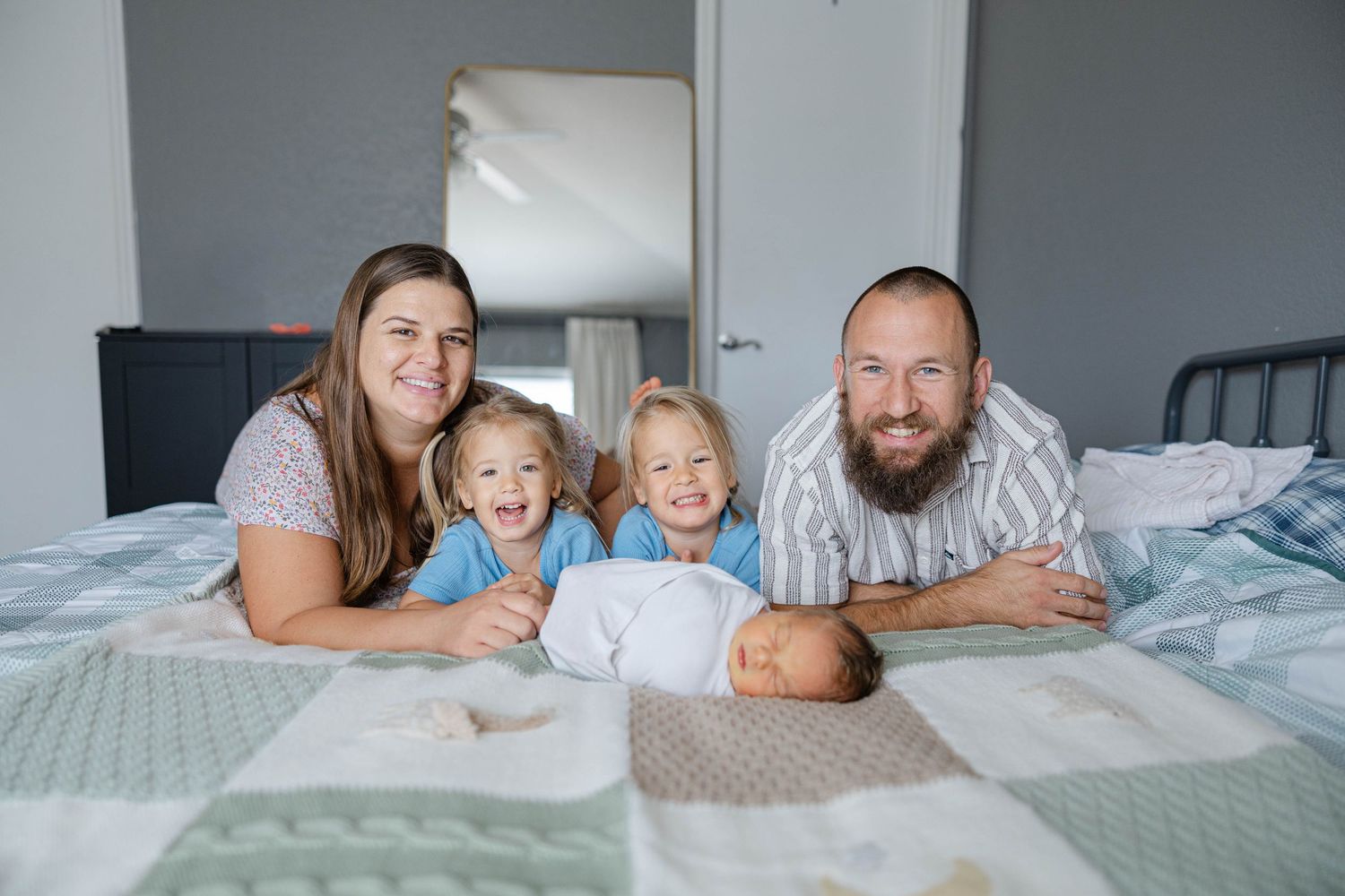 Family lying together on a bed during a lifestyle family session.
