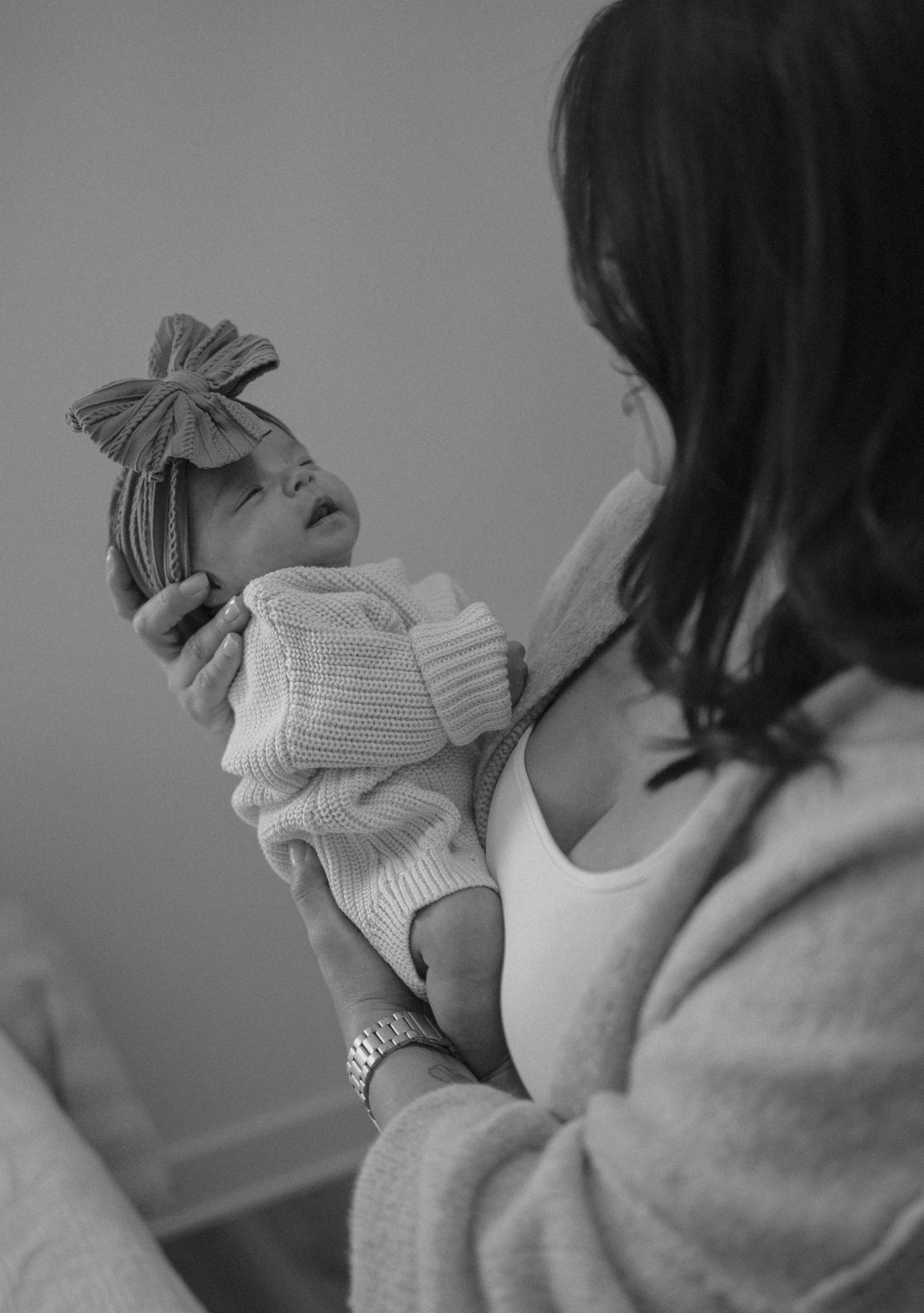 Black and white lifestyle newborn photo of a parent holding their baby close to their chest.