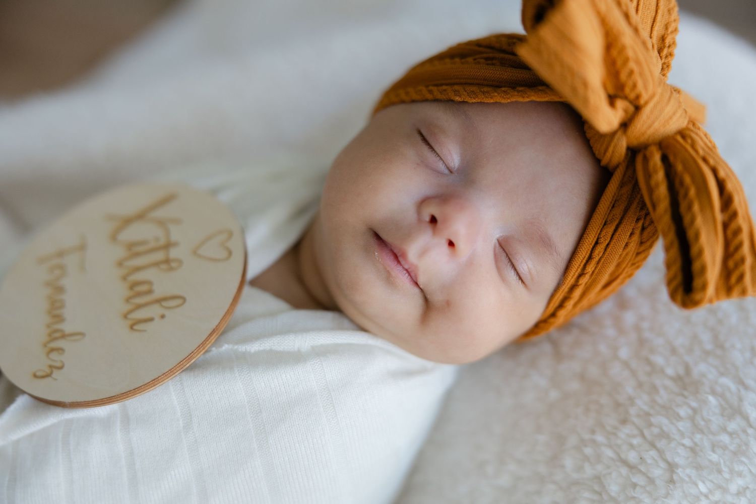 Lifestyle family session featuring parents sitting on a bed with their newborn baby in a relaxed, light-filled space.