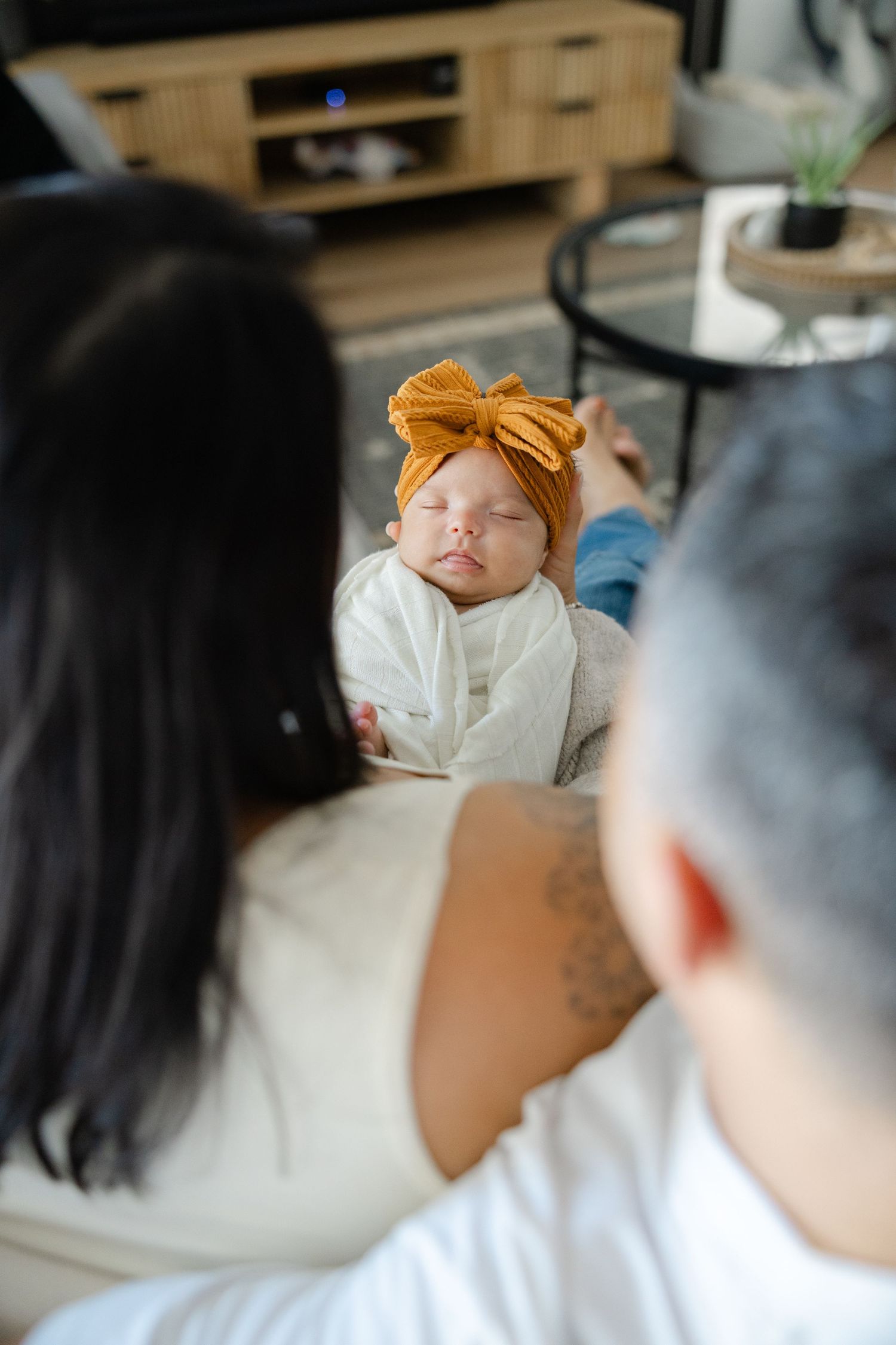 Parents sitting together on a bed holding their newborn baby during a relaxed in-home lifestyle session.