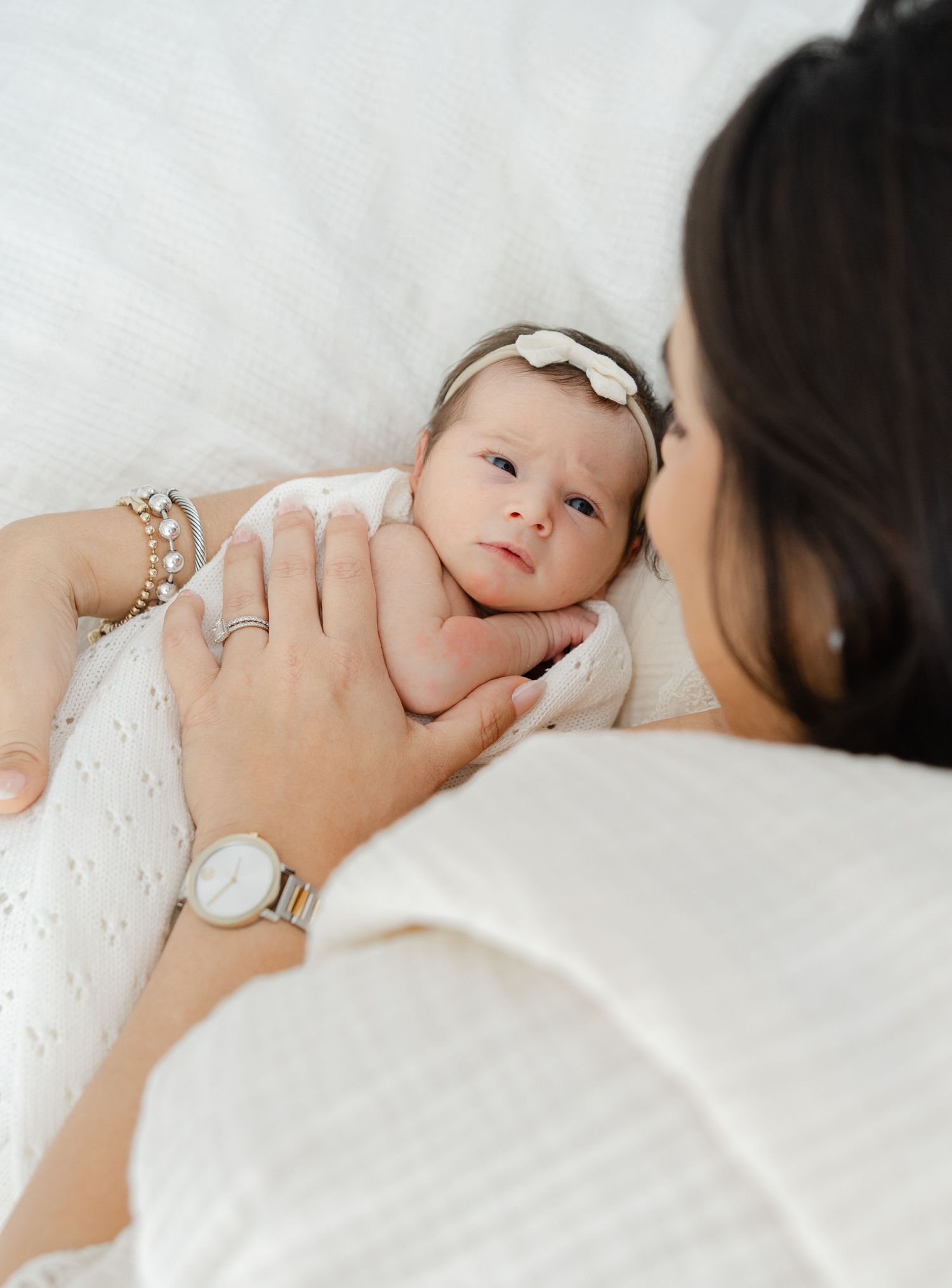 Mother holding her newborn baby close during a soft, light-filled lifestyle newborn photography session.