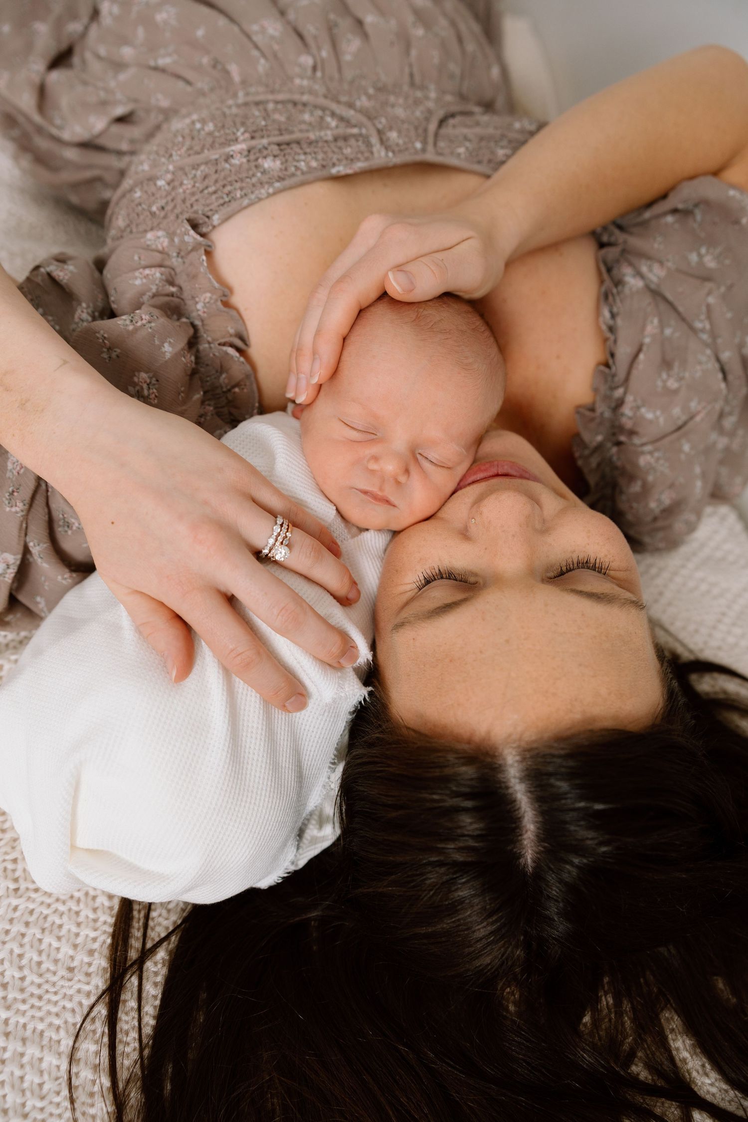 Mother holding her newborn near a window during a lifestyle photography session.