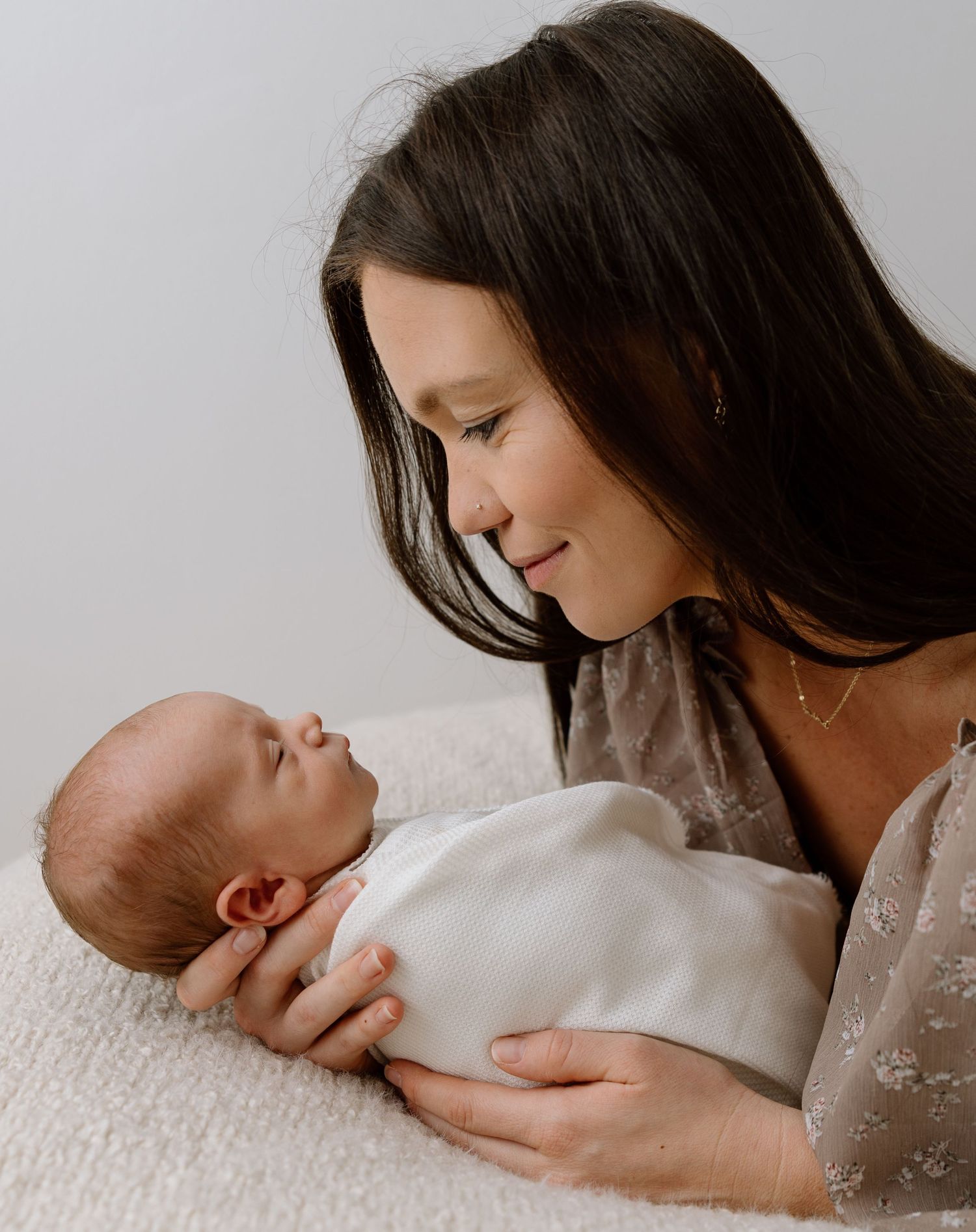 Mother lying down holding her newborn baby during a lifestyle session.
