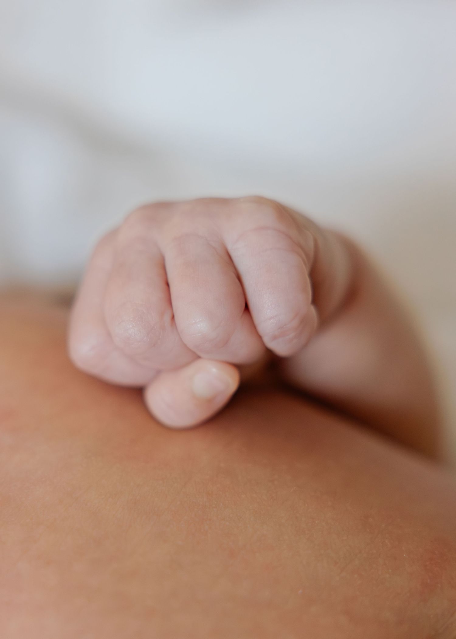 Close-up of a tiny baby hand resting gently on skin showing delicate newborn details.
