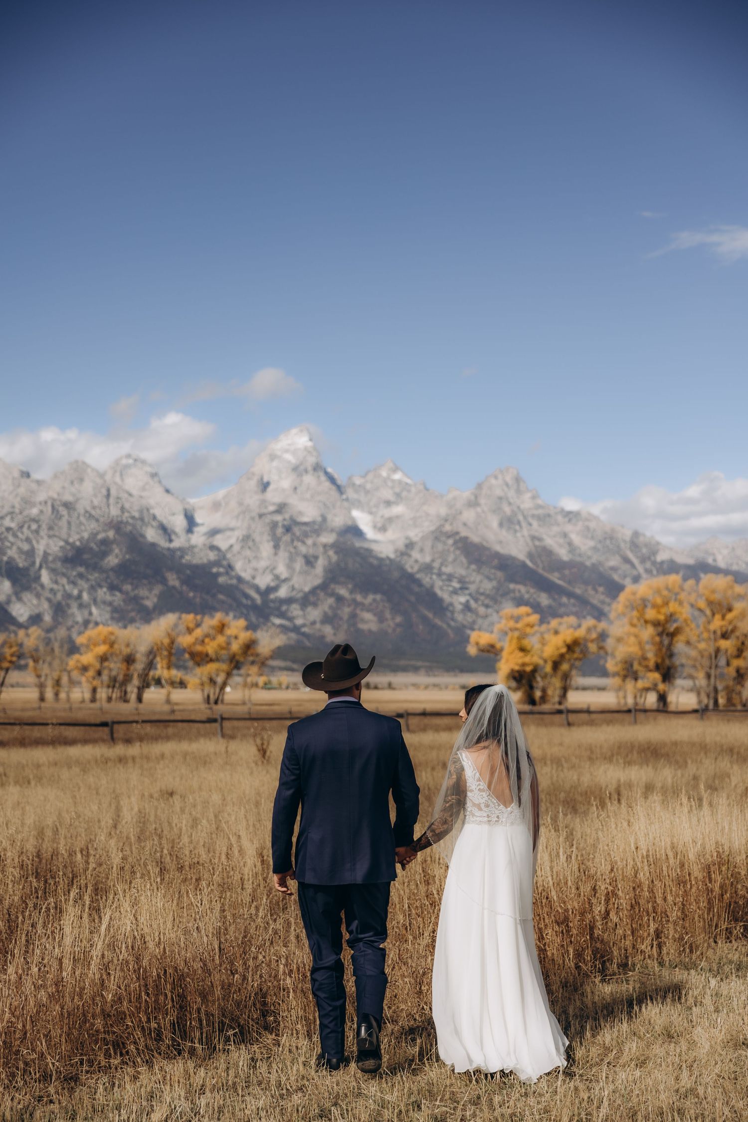 A mountain wedding ceremony takes place on a scenic hilltop with dramatic peaks in the background.