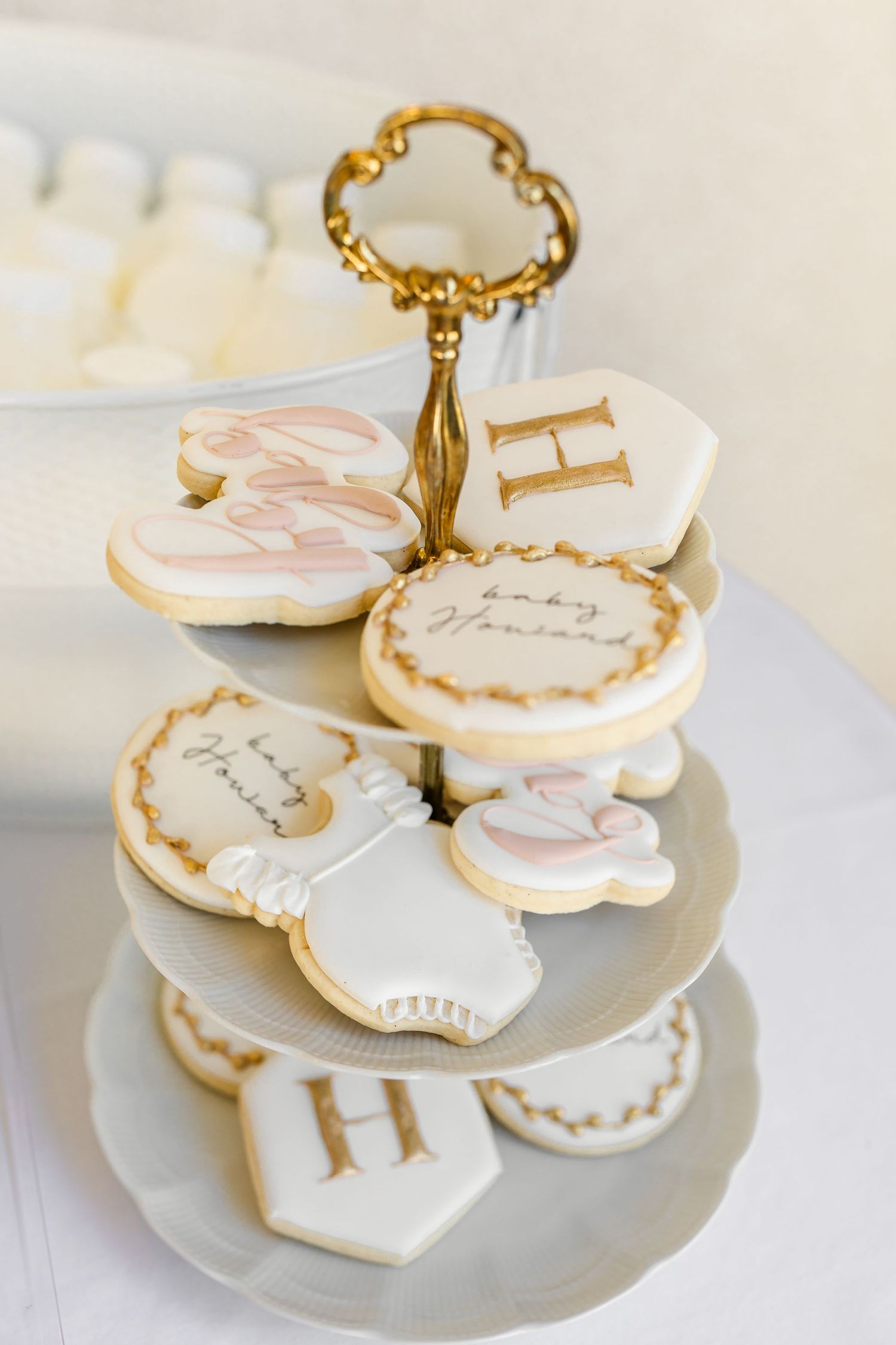 Elegant white and pink sugar cookies with gold trim arranged on a tiered serving plate with ornate gold handle photographed by Chelsee Rawe