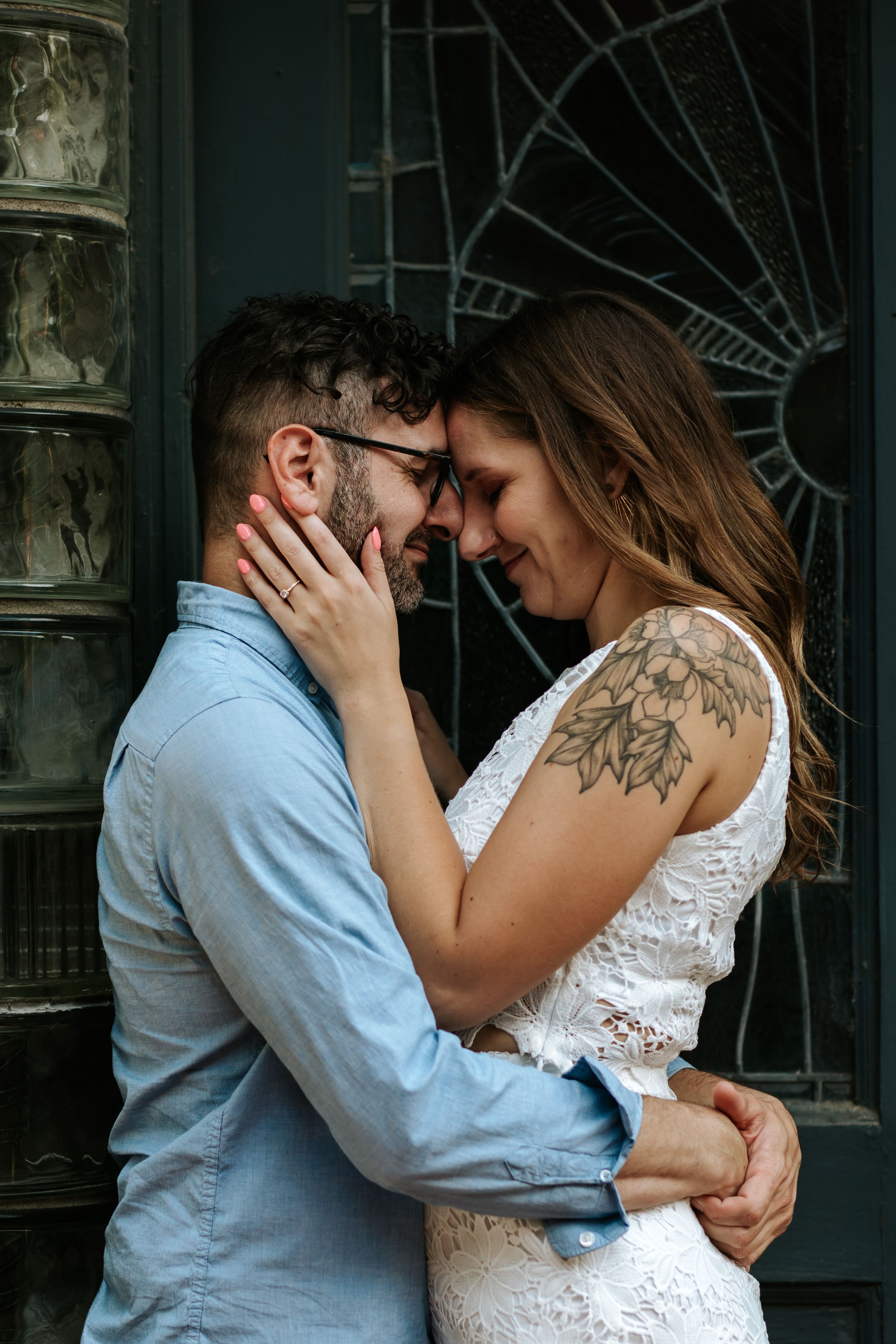 A romantic couple shares an intimate moment in front of a vintage-style door with ornate metalwork details.